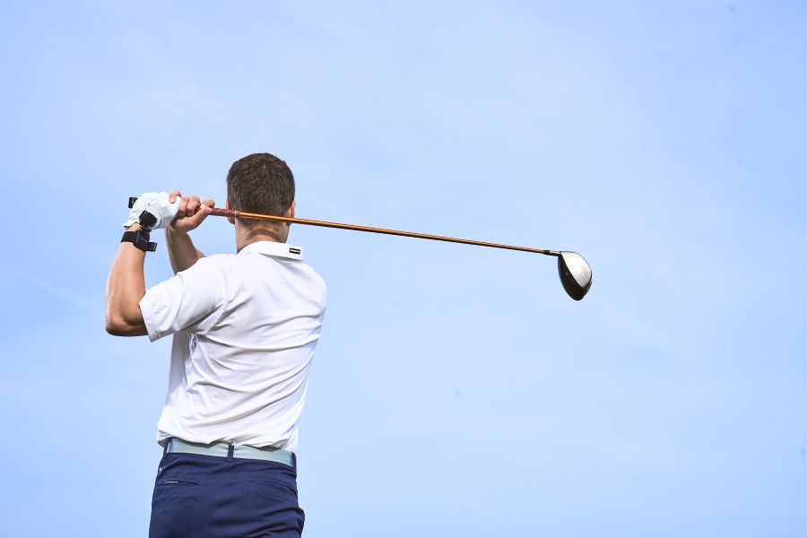 golf player with driver on golf course after shot