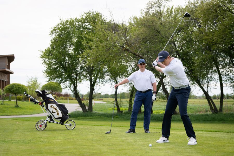 two golfers playing golf on the course and hitting from tee box
